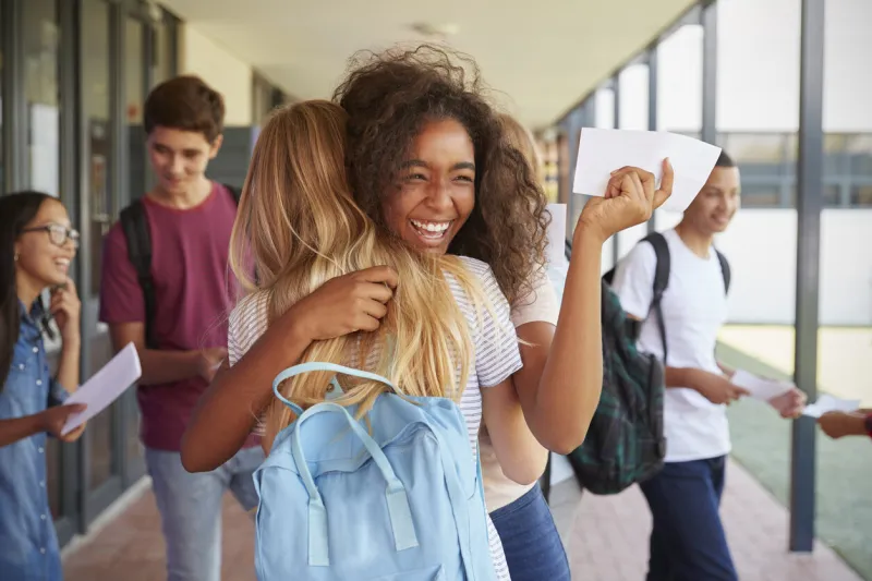 two girls celebrating exam results in school corridor