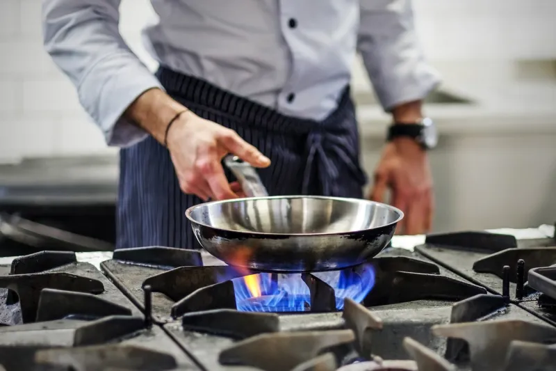 frying pan on a gas stove chef controls the cooking process