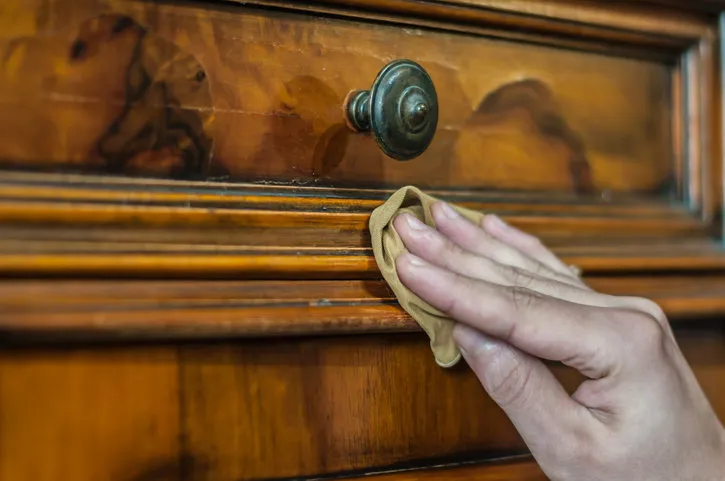 hand applying oil and wax on a old wood furniture