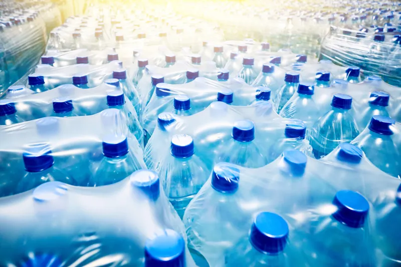 many packaged blue mineral water bottles in stock in a store or market