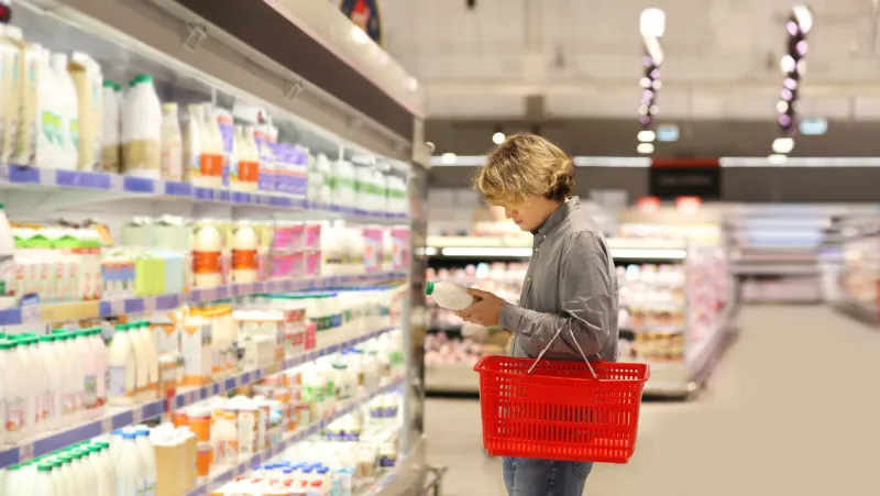 teenager shopping in supermarket, reading product information