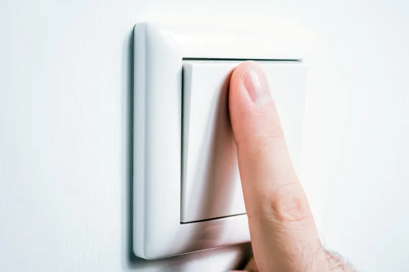 a male finger touching a light switch to turn the light on or off