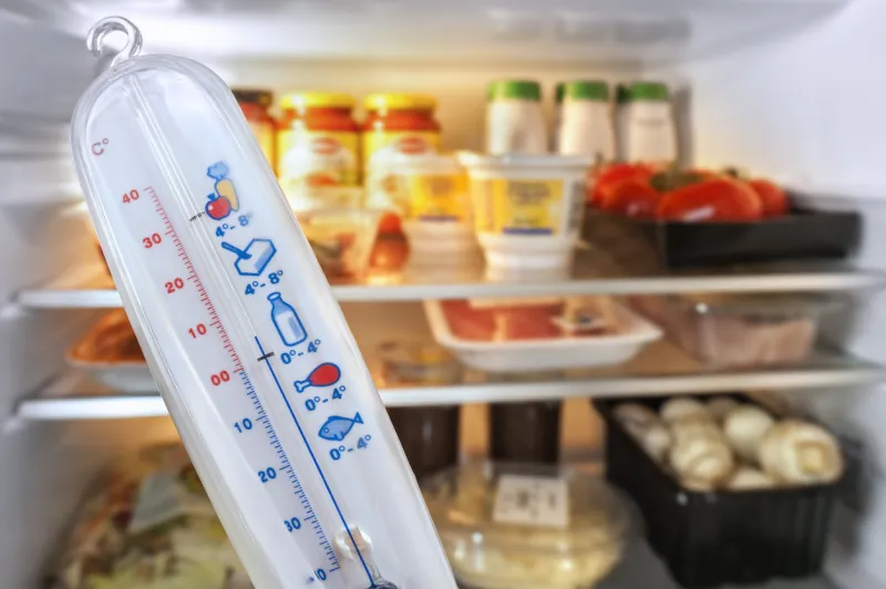 thermometer in front of open fridge   refrigerator filled with food in kitchen