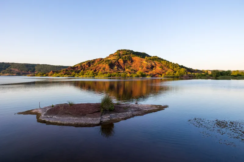 view on the ancient volcano of cérébou at the edge of the salagou lake at sunset
