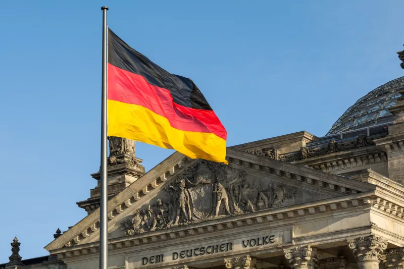 german flag fluttering front of reichstag building berlin, germany