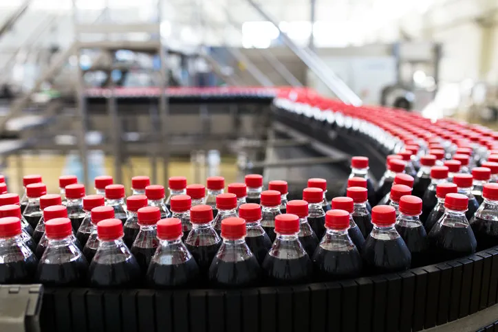 bottling factory - black juice or soft drink bottling line for processing and bottling juice into bottles selective focus