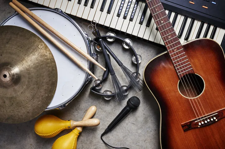 a group of musical instruments including a guitar, drum, keyboard, tambourine