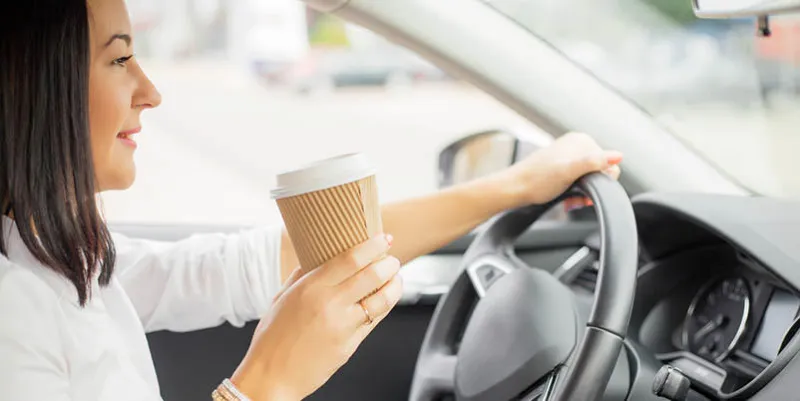 woman driving and holding a coffee cup