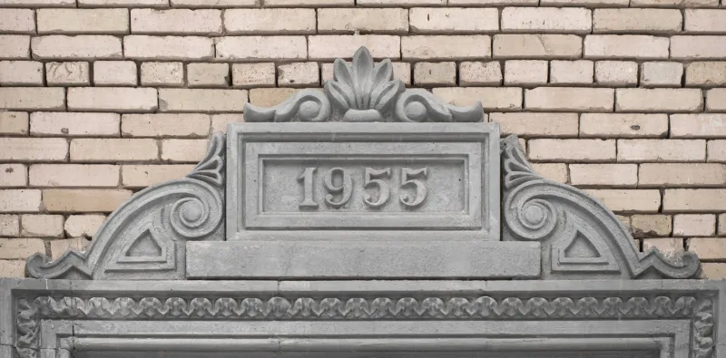 sculpted inscription 1955 above the entrance group on the facade of the house