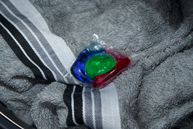 a colorful washing gel in capsule on laundry in a washing machine, washing clothes at home