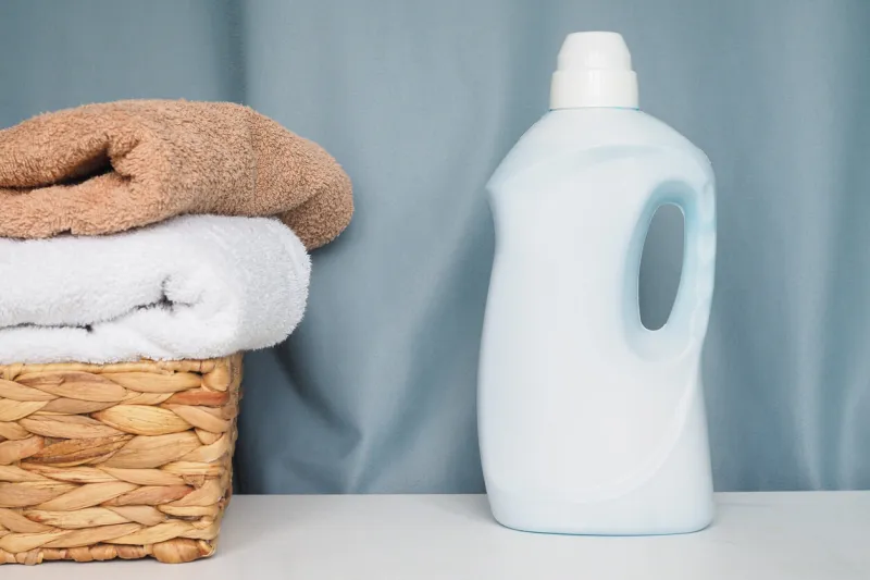 brown basket with towels and laundry detergent on blue background