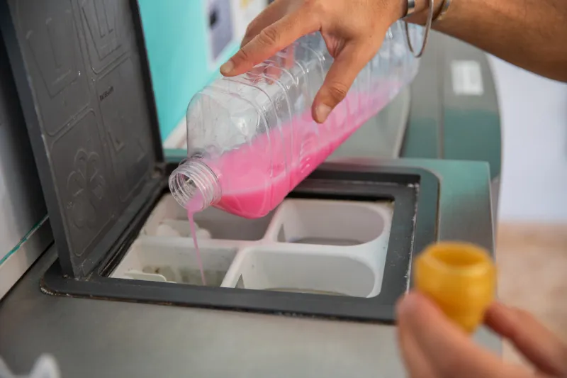 a man pours detergent for washing clothes into the washing machine in a laundromat