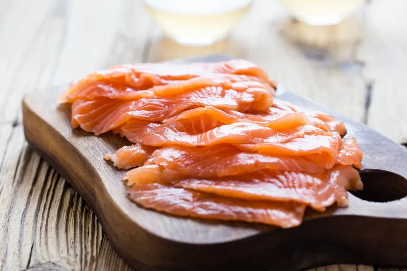 homemade smoked salmon on wooden board, sliced, close up, selective focus