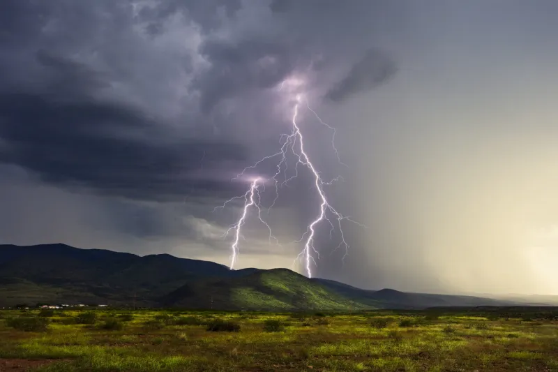 twin lightning bolts strike the peloncillo mountains during a monsoon storm near clifton, arizona