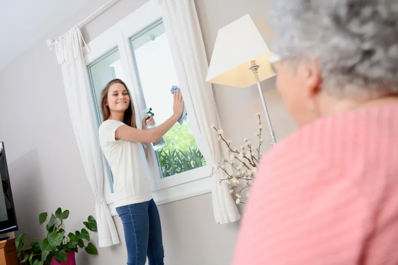 cheerful young girl helping with household chores elderly woman at home