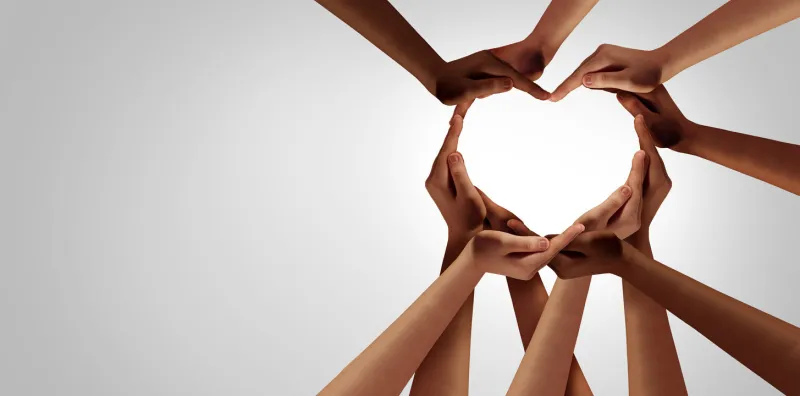 unity and diversity partnership as heart hands in a group of diverse people connected together shaped as a support symbol expressing the feeling of teamwork and togetherness