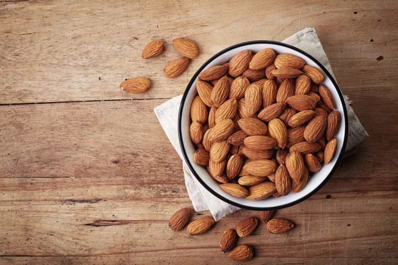 white bowl of almonds on wooden background