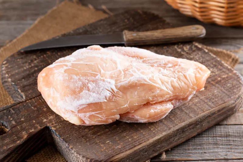frozen chicken fillet on a cutting board on a wooden table frozen food