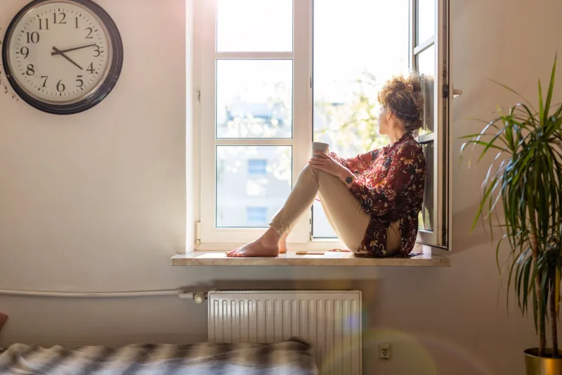 beautiful young woman sitting at a window sill having rest