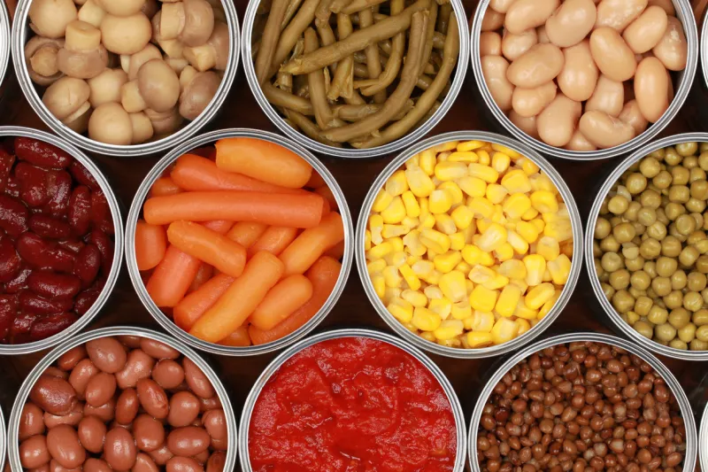 different kinds of vegetables such as corn, peas and tomatoes in cans