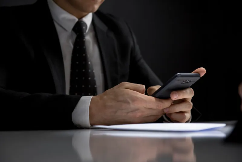 portrait of businessman using his mobile phone making illegal private deal in a dark room