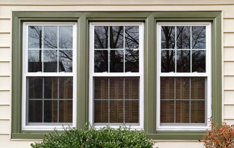 three new replacement windows with green trim on front of house horizontal