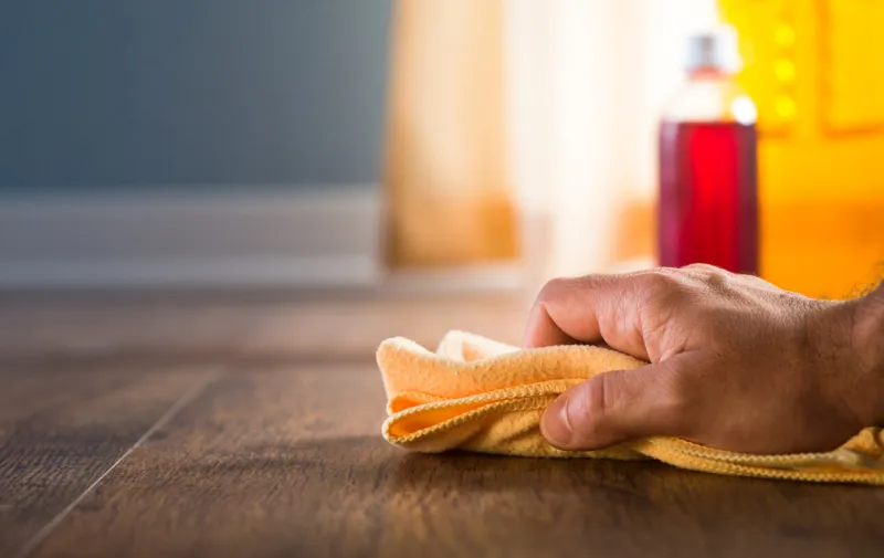 male hand applying wood care products and cleaners on hardwood floor surface