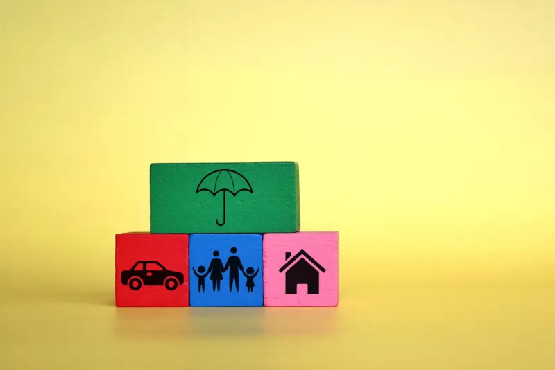 insurance and protection concept wooden cubes with umbrella, car, family and house icon