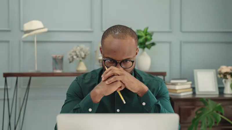 young african american man is thinking in front of a laptop