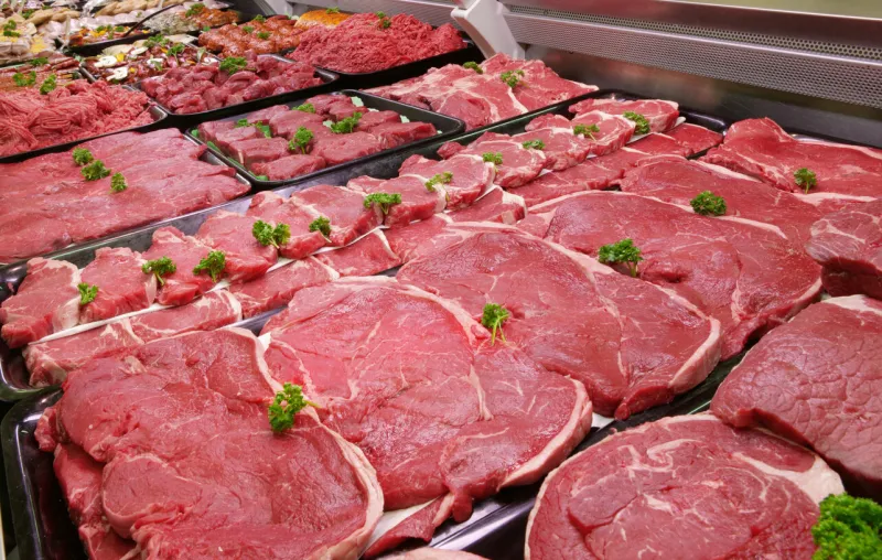a selection of raw beef in a refrigerated counter