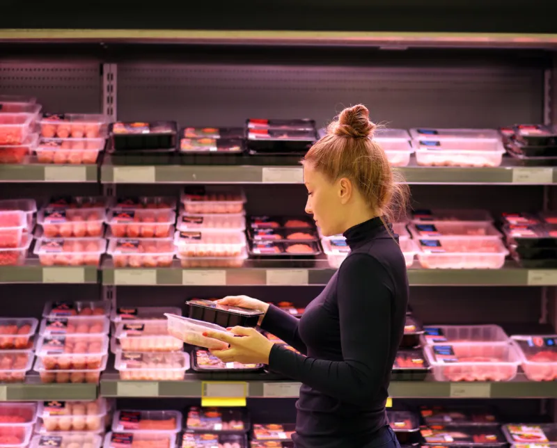 woman purchasing a packet of meat at the supermarket