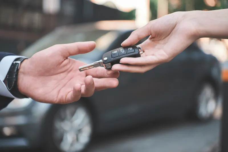 car dealershipyoung man receiving car key from saleswoman