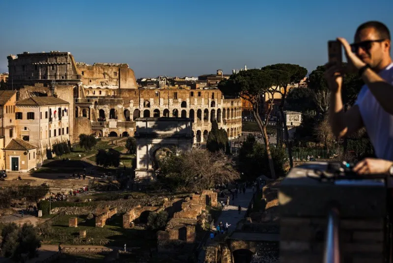a tourist takes a photo from the palatine hill (palatino) with the colosseum (colosseo, colisee) in background on february 28, 2019 in rome (photo by laurent emmanuel   afp)