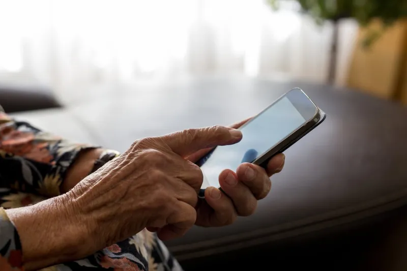 closeup of old woman hands holding mobile phone
