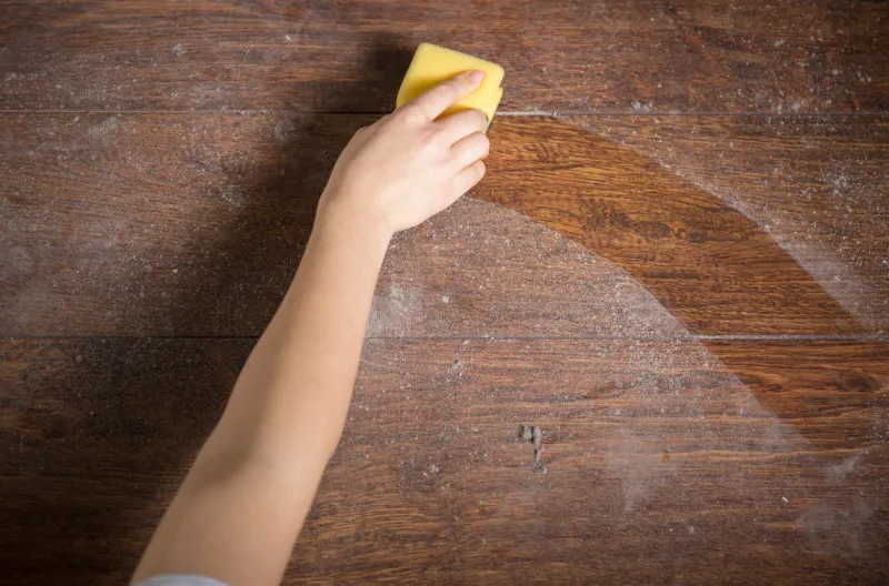 using yellow sponge for cleaning dusty wood