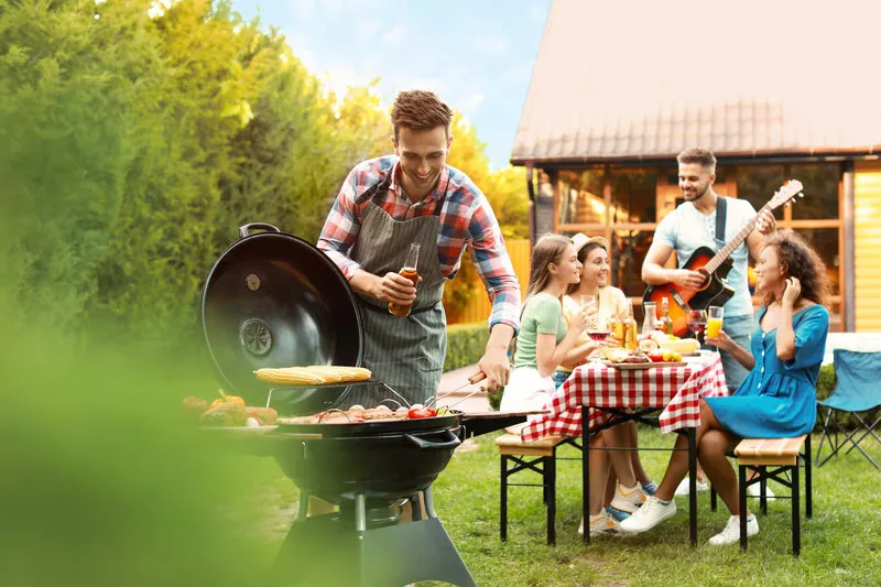 group of friends at barbecue party outdoors young man near grill