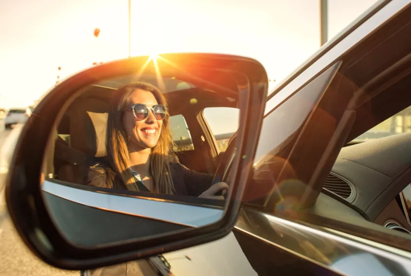 beautiful businesswoman in rear view mirror with sunglasses smiling