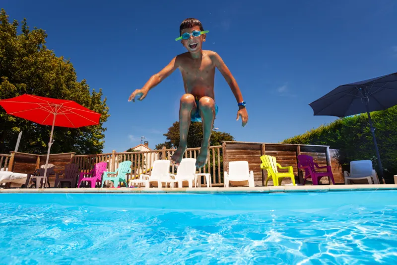 little happy screaming boy child jump in the swimming pool mid air portrait