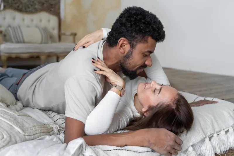 multiethnic couple afro american man embracing kissing caucasian woman at home, black boyfriend and caucasian girlfriend lying in bed have fun together human relationships