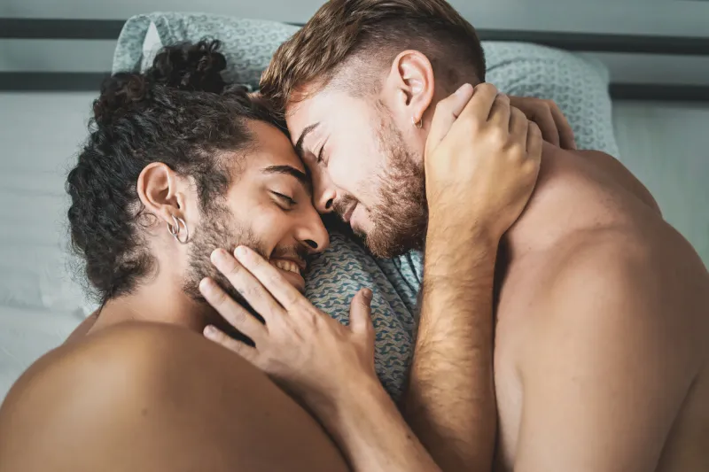 homosexual male couple caressing shirtless in the bed - concept of gay love and diverse people lifestyle