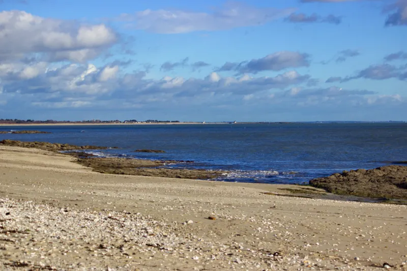 beach at sarzeau in morbihan in autumn with no one the beach has some seaweed and sand, the sky is blue and cloudy