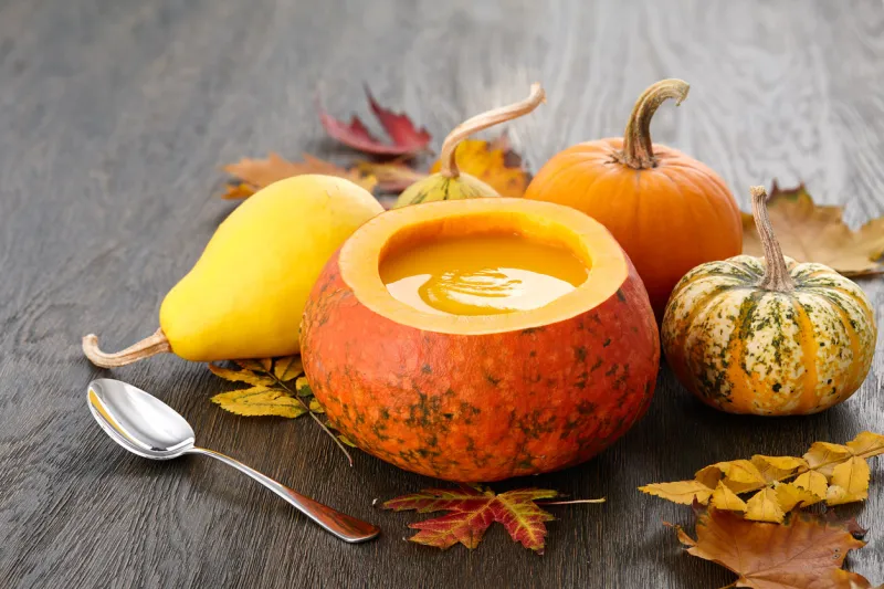 fall pumpkin soup in big decorative pumpkin on dark wooden background