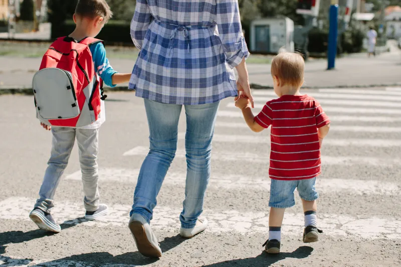 walking to school mother with children crossing a road on way t