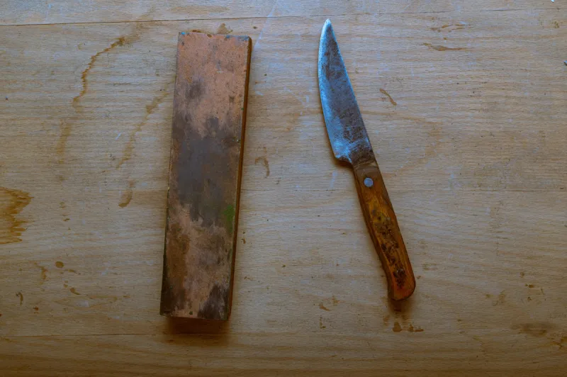 an old homemade knife and a whetstone sharpen a knife with a sharpening stone top