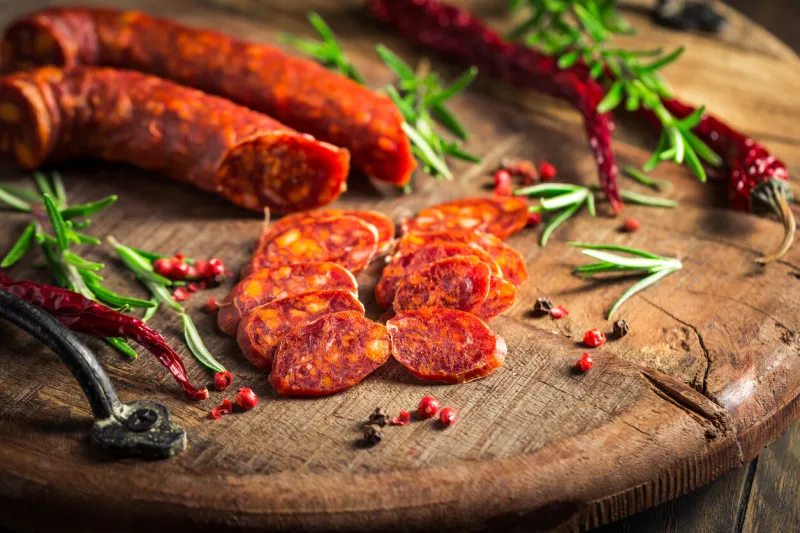 red spanish chorizo sausage with herbs and spices on wooden cutting board