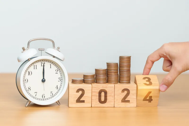 happy new year with vintage alarm clock and flipping 2023 change to 2024 block resolution, goals, plan, action, money saving, retirement fund, pension, investment and financial concept