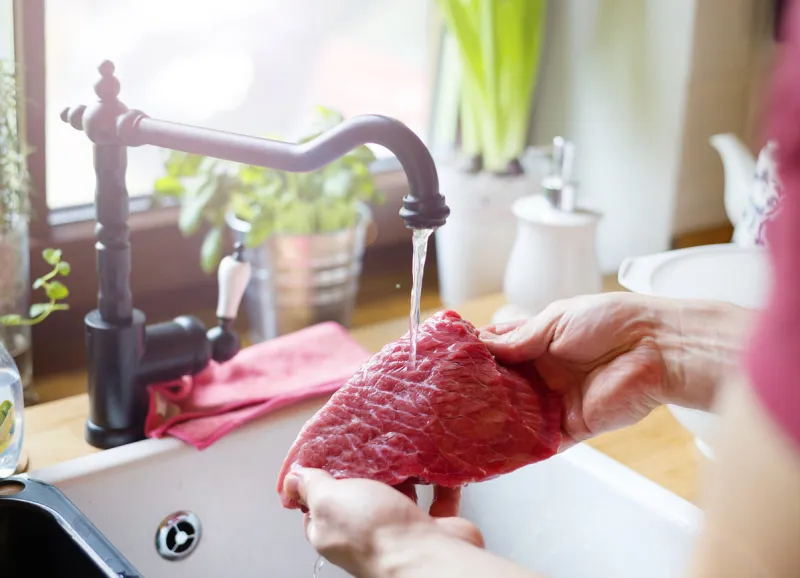 ungrcognizable man in the kitchen preparing beef steak