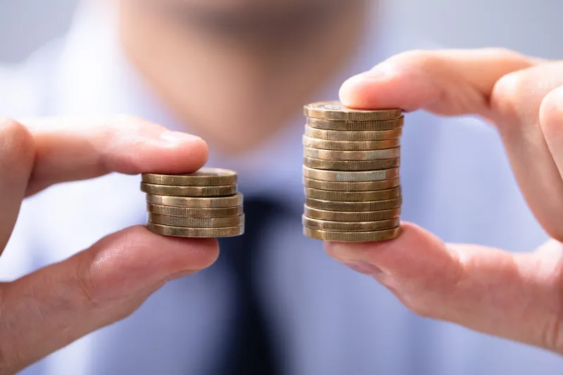 man holding two coin stacks to compare