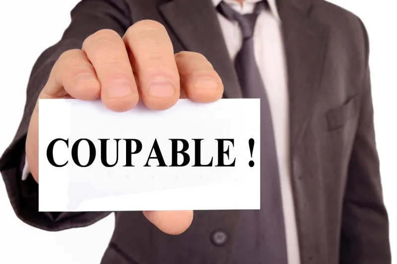 homme tenant une carte sur laquelle est écrit coupable en français