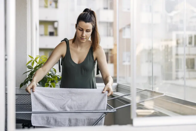 spreading laundry on the balcony the woman does the housework a woman dressed in casual olive green clothes spreads her lingerie and towel along the wire on the terrace